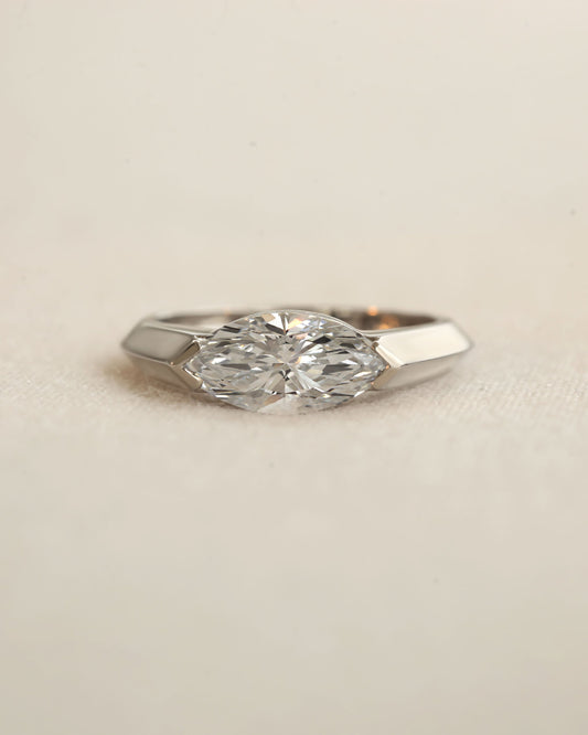 Marquise cut diamond bezel ring in white gold on white background.