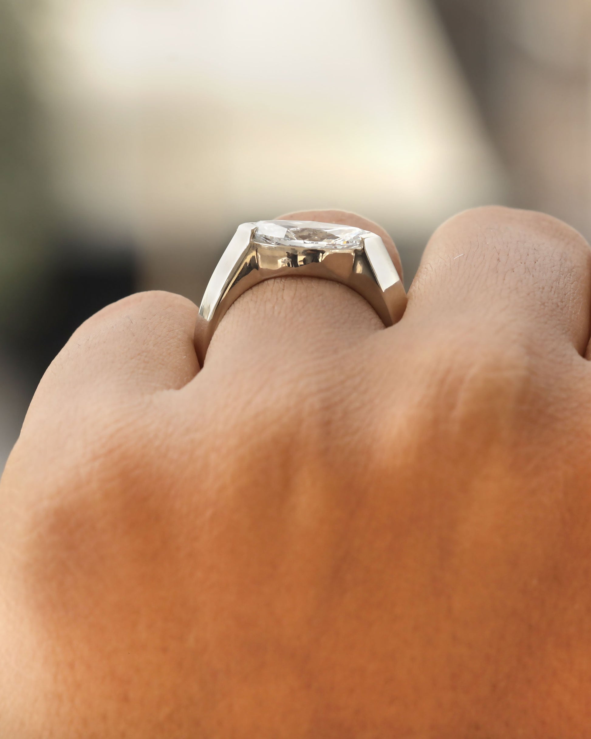 Hand wearing a marquise cut diamond bezel ring in white gold.