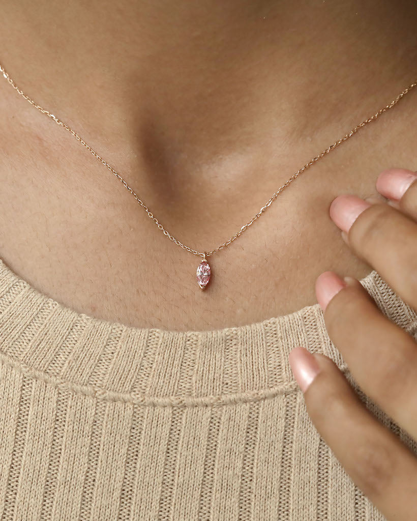 Person wearing marquise cut lab diamond solitaire pendant necklace in yellow gold.