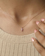 Person wearing marquise cut lab diamond solitaire pendant necklace in yellow gold.