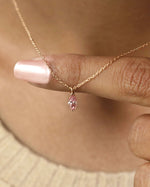 Person wearing marquise cut lab diamond solitaire pendant necklace in yellow gold.