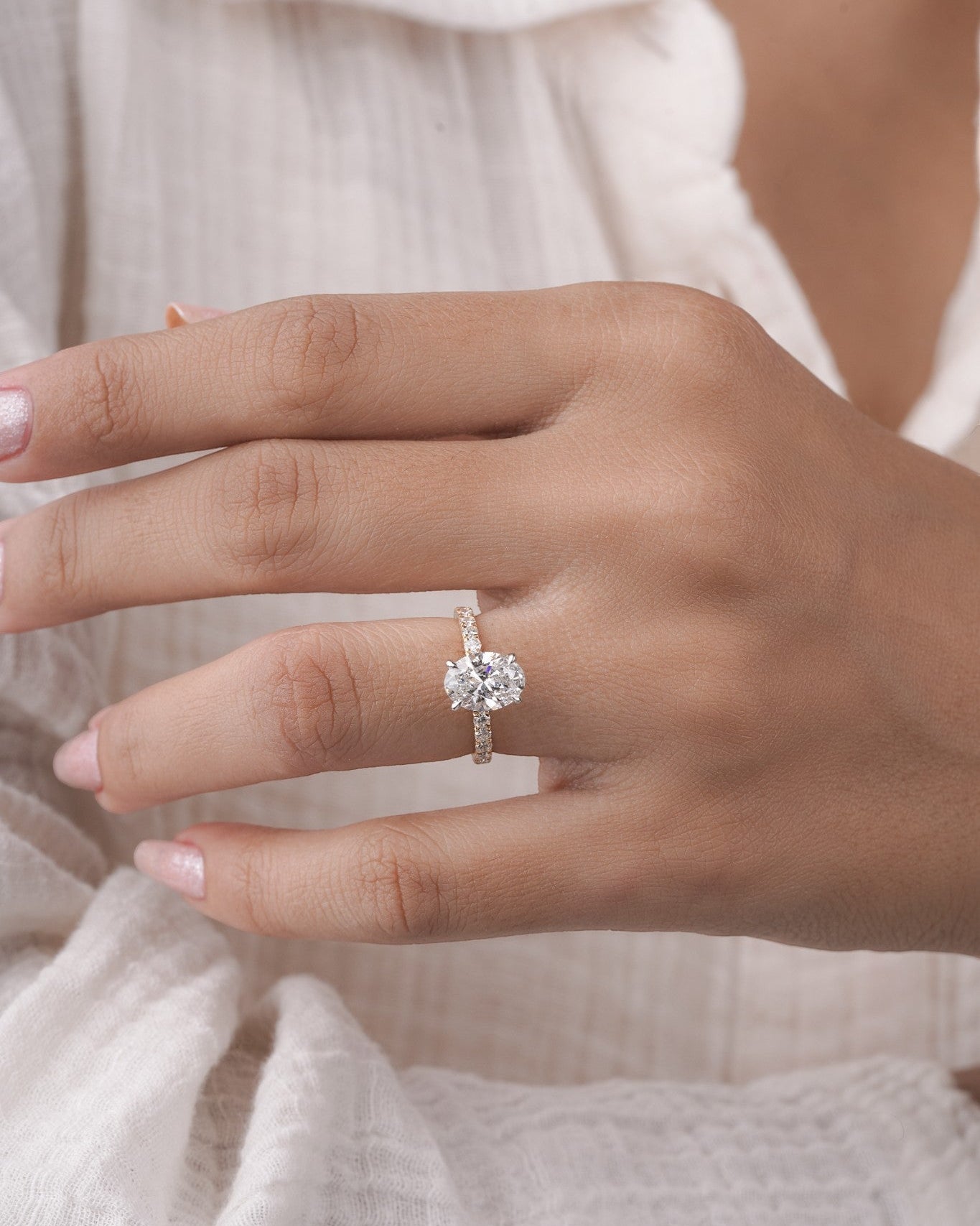 Hand wearing oval cut diamond ring in yelllow gold.