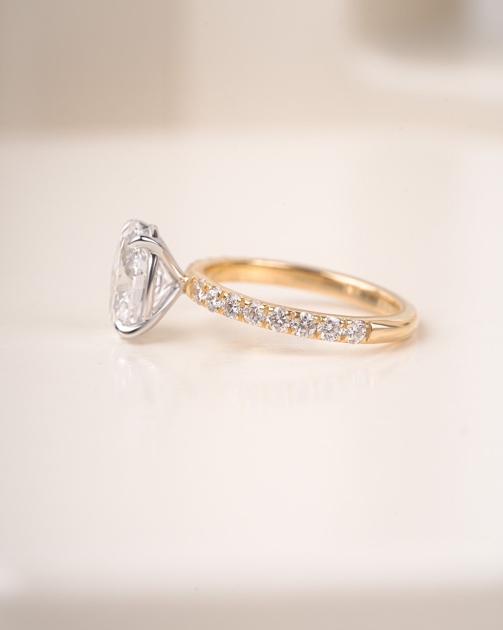 Oval cut diamond ring in yelllow gold on a white background.