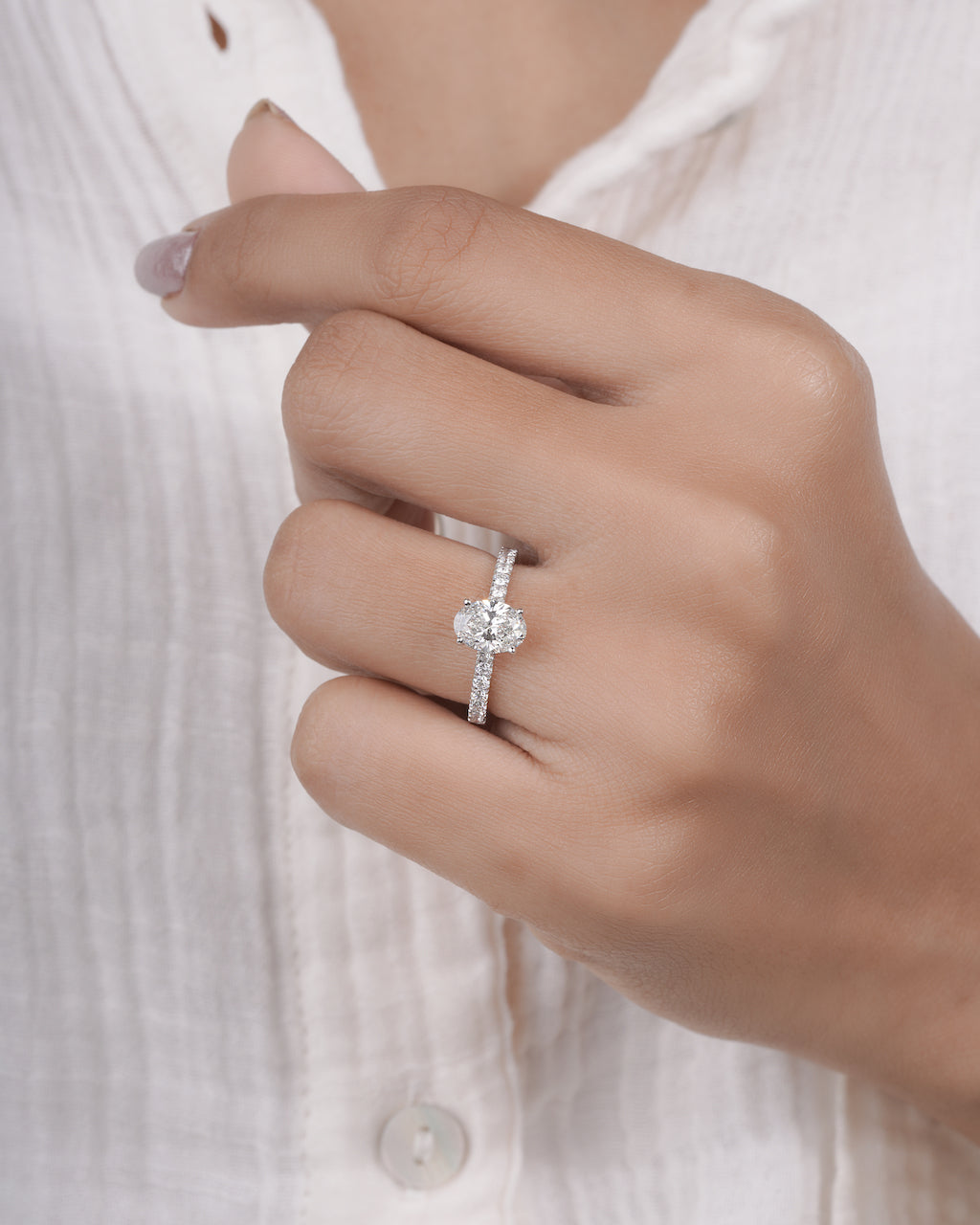 Hand wearing oval cut lab grown diamond engagement ring in white gold.

