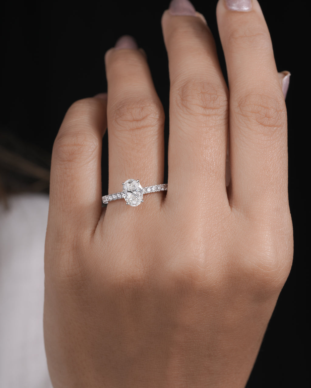 Hand wearing oval cut lab grown diamond engagement ring in white gold.

