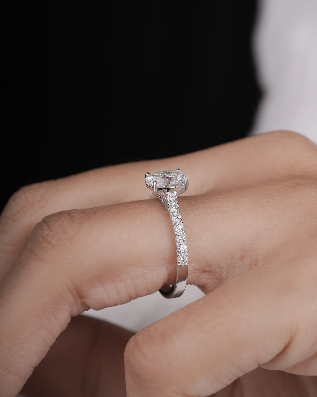 Hand wearing oval cut lab grown diamond engagement ring in white gold.

