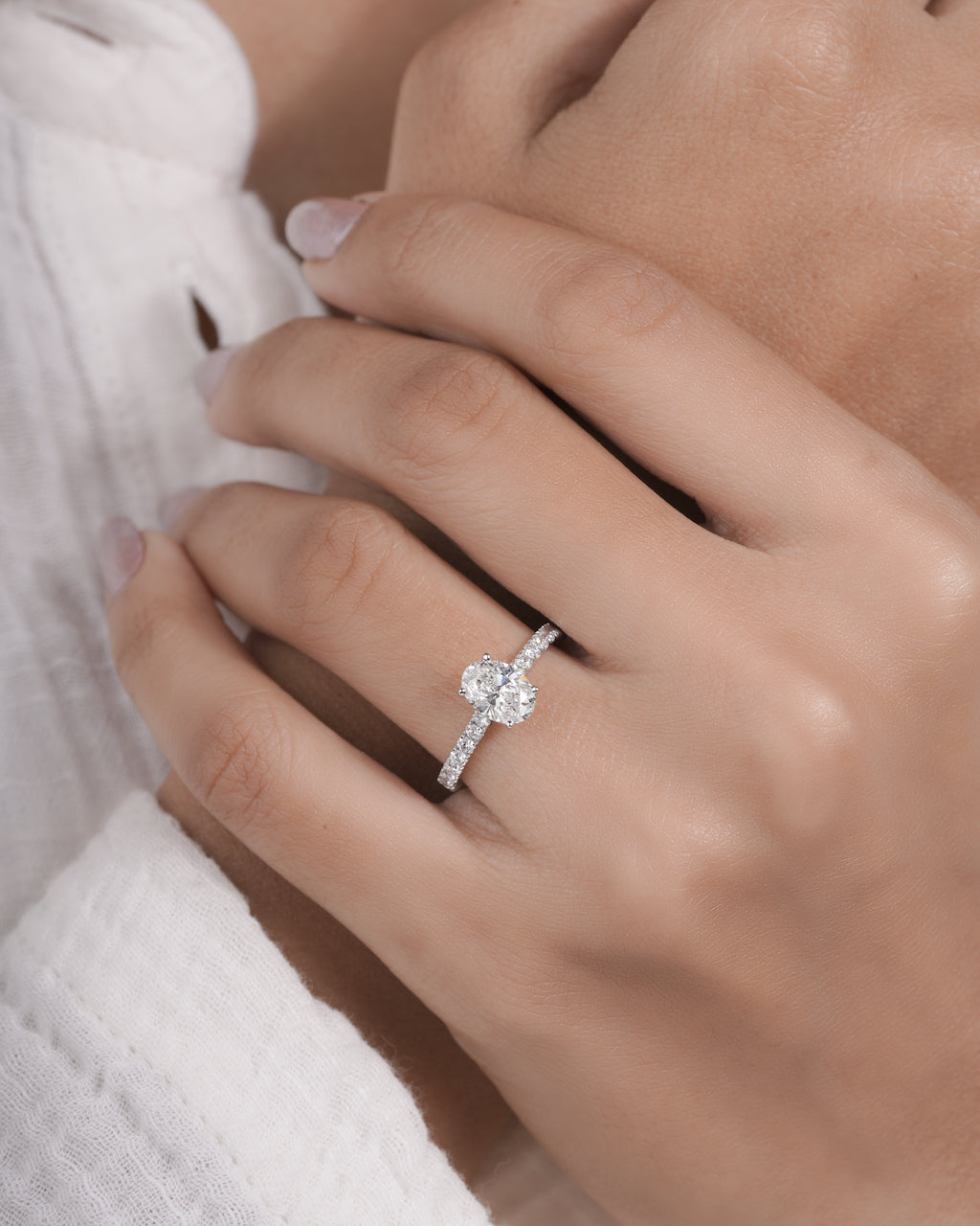 Hand wearing oval cut lab grown diamond engagement ring in white gold.


