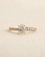 Close up shot of oval cut lab-grown diamond engagement ring in yellow gold.
