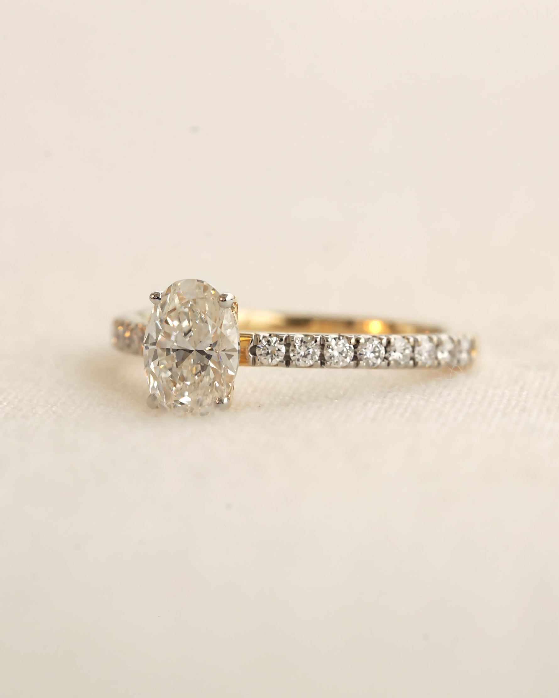 Close u shot of oval cut lab-grown diamond engagement ring in yellow gold.
