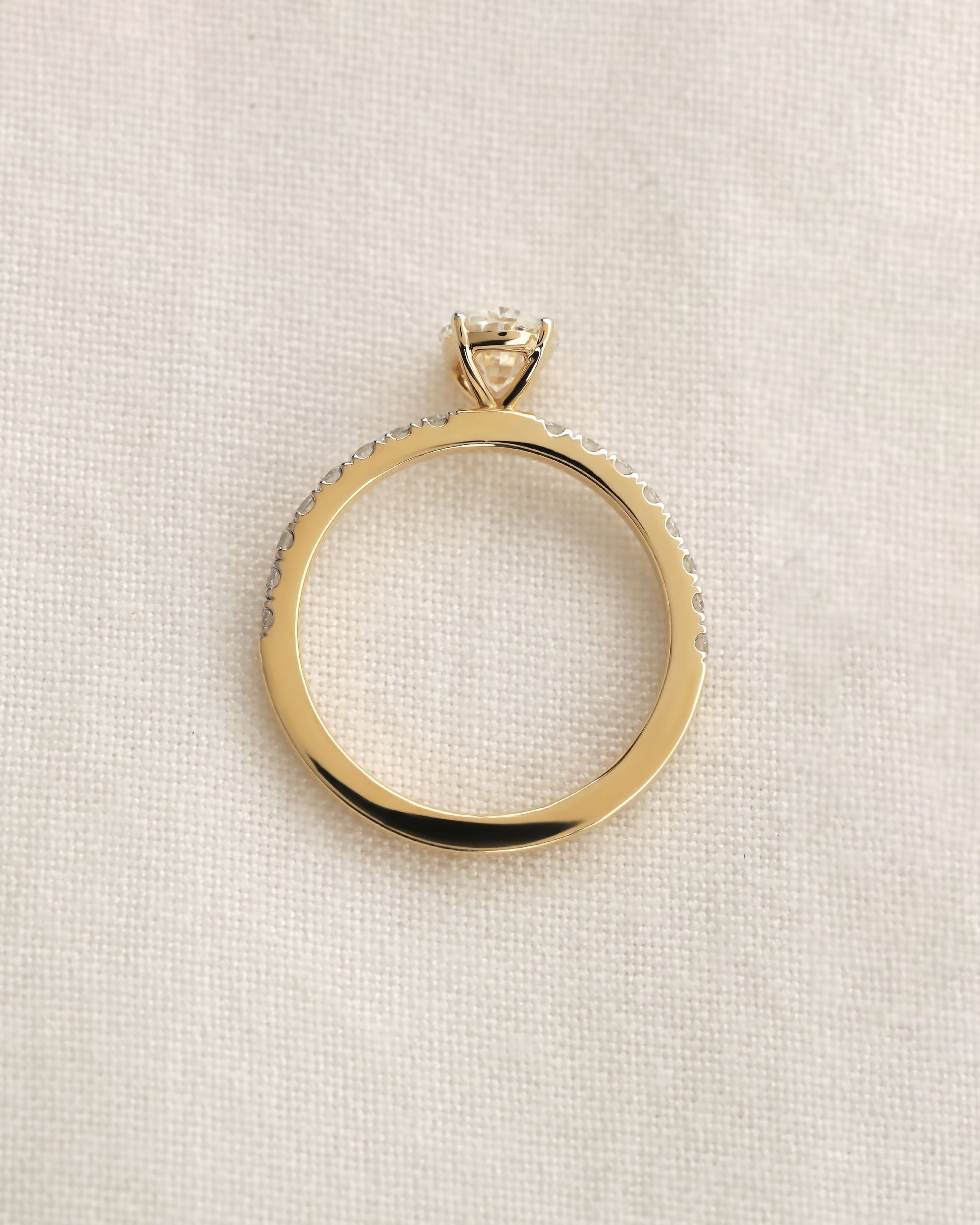 Close up shot of  oval cut lab-grown diamond engagement ring in yellow gold.
