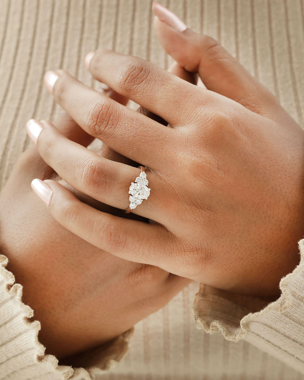 Hand wearing oval cut diamond engagement ring in rose gold.
