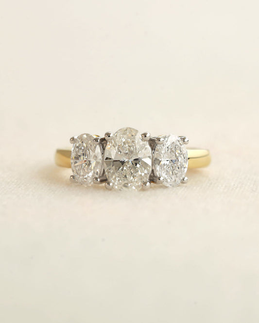 Oval cut three stone diamond on a white background.