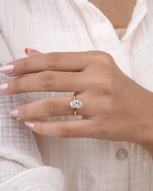 Hand wearing oval diamond engagement ring in yellow gold.