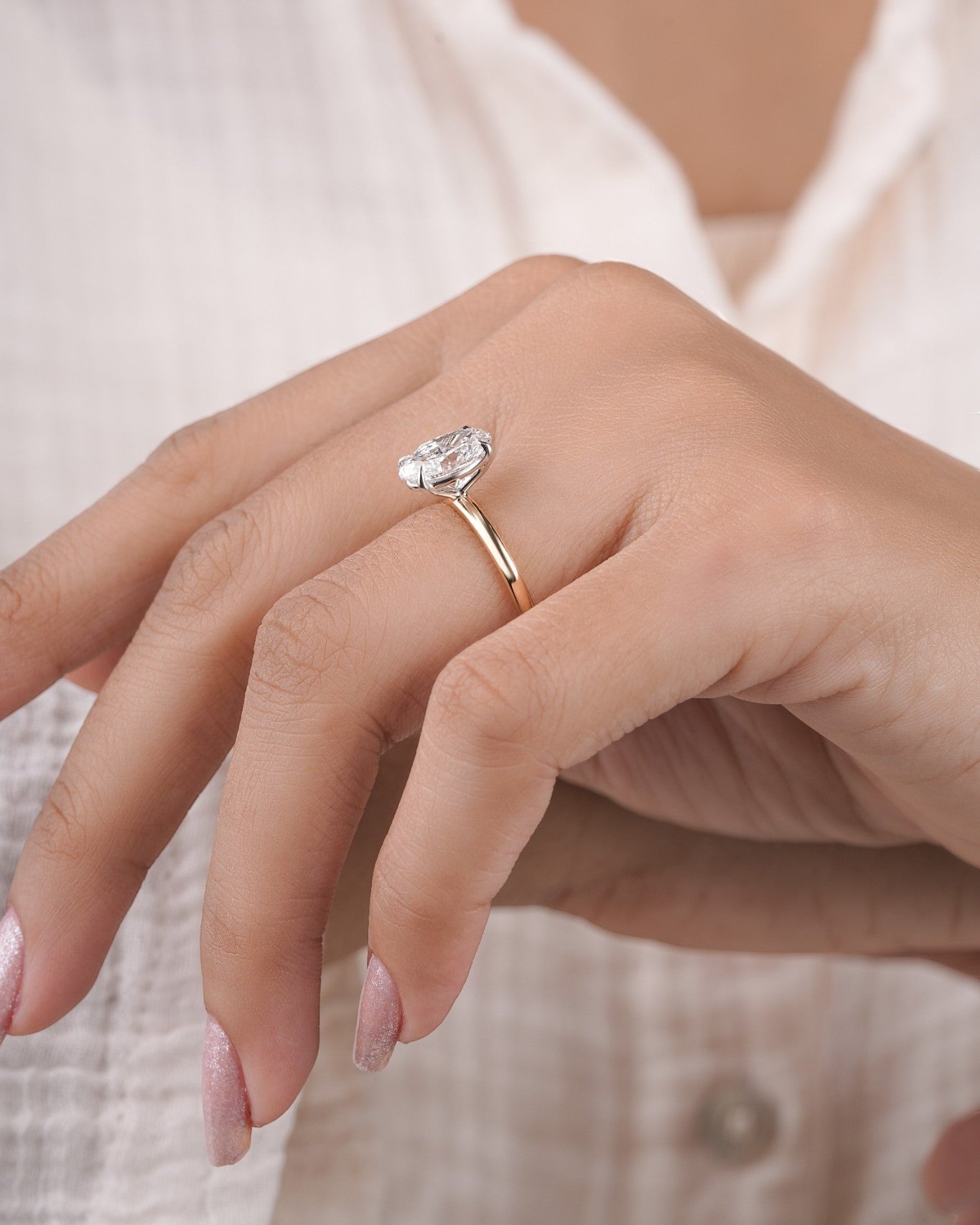 Hand wearing oval diamond engagement ring in yellow gold.