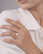 Hand wearing oval diamond engagement ring in yellow gold.