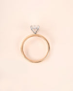 Oval diamond engagement ring in yellow gold on a white background.