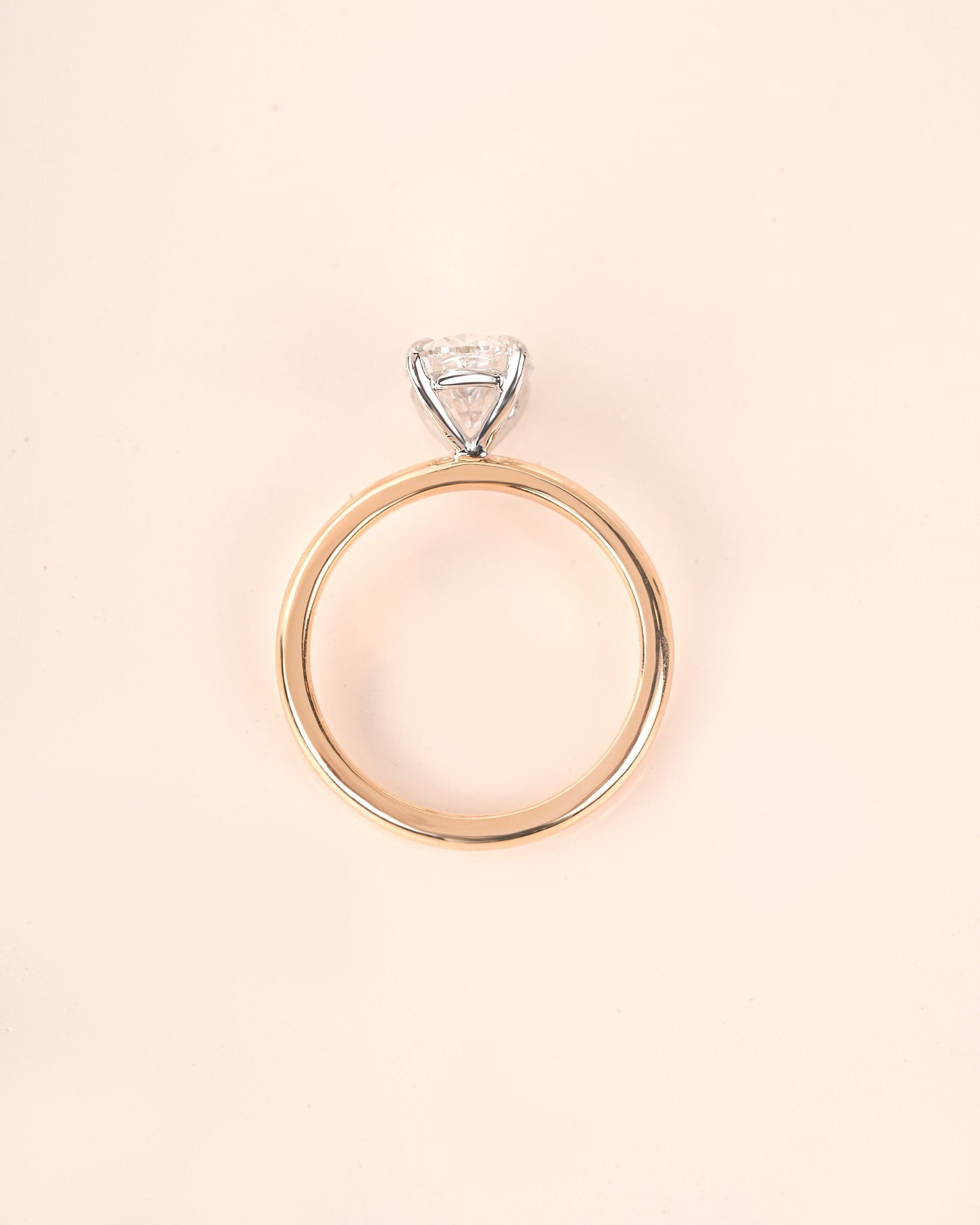Oval diamond engagement ring in yellow gold on a white background.