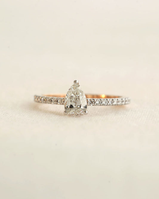 Pear cut lab-grown diamond ring on a light textured background.