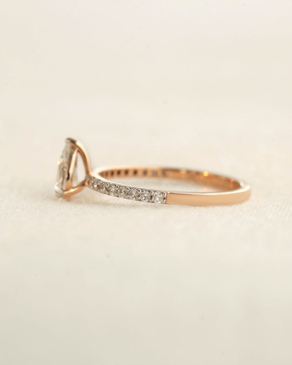 Side shot of pear cut diamond ring on white background.