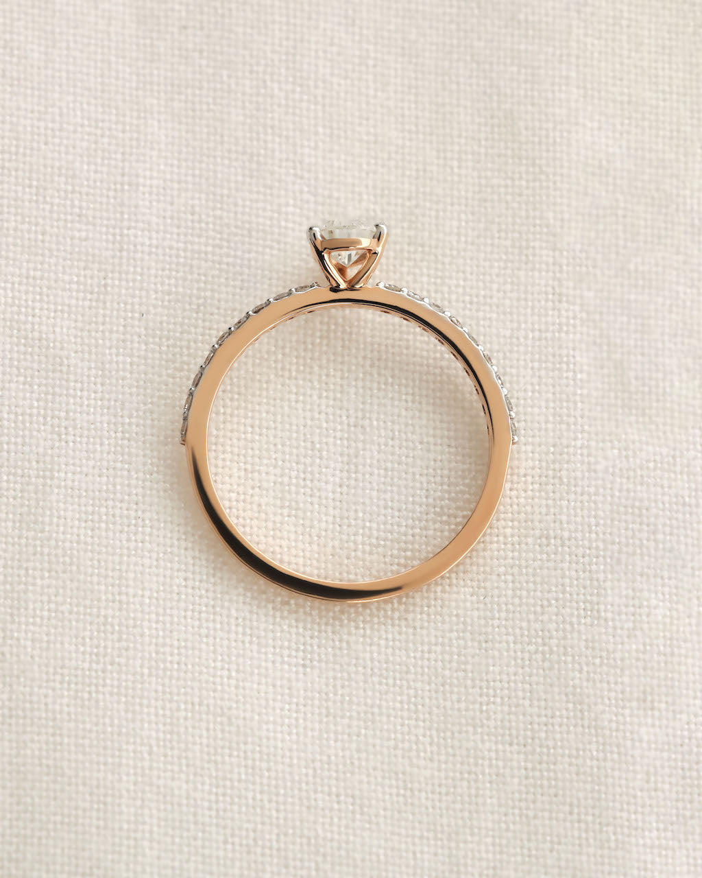 Pear cut lab grown diamond engagement ring in 14ct yellow gold on a textured background.