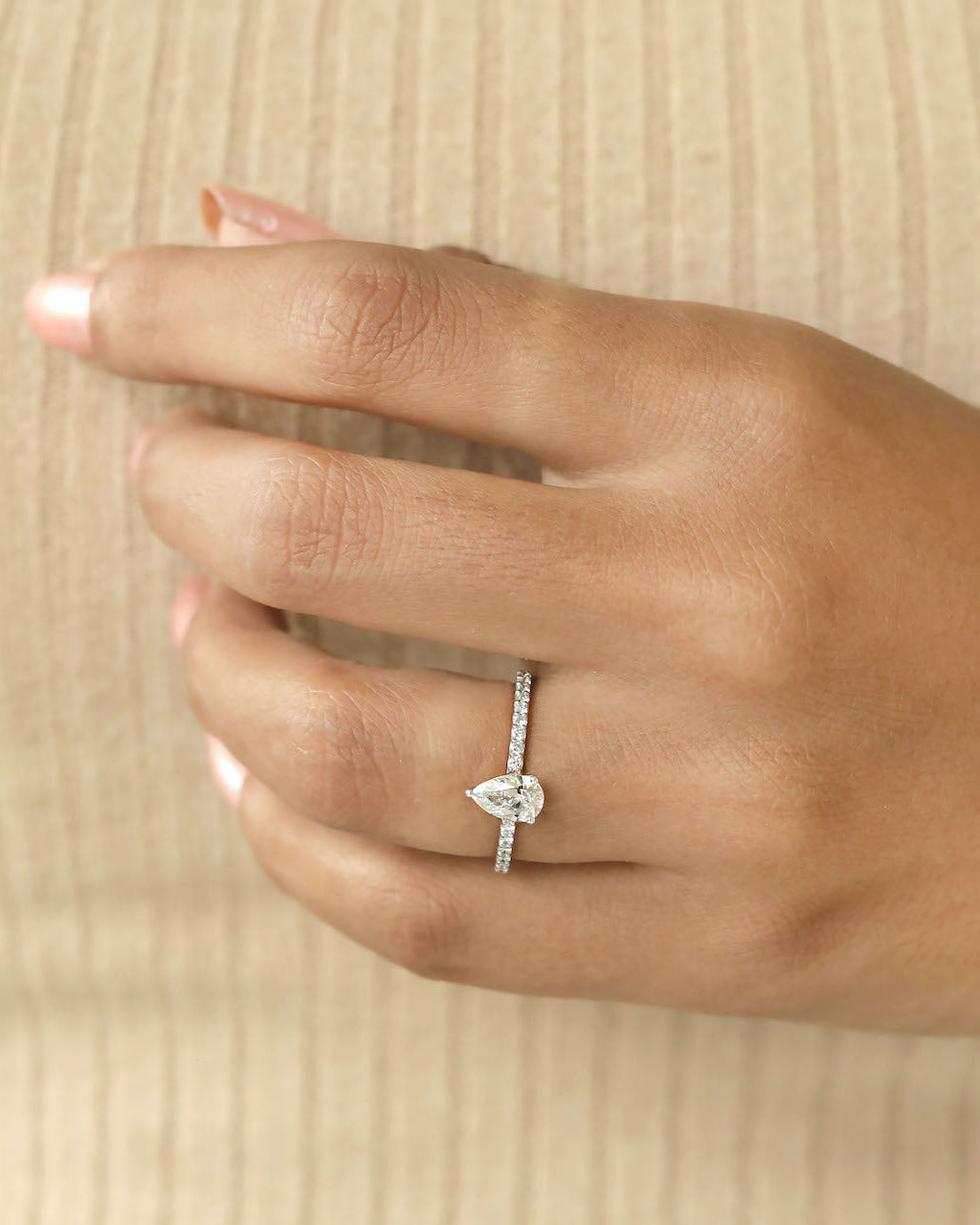 Hand wearing a pear cut diamond ring.