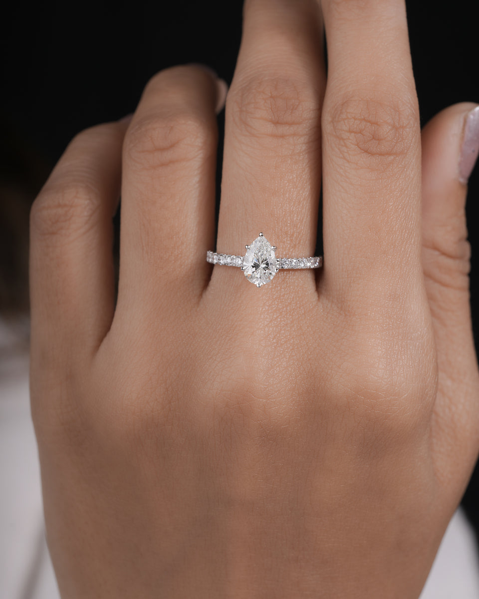  Hand wearing pear cut lab grown diamond engagement ring in white gold.
