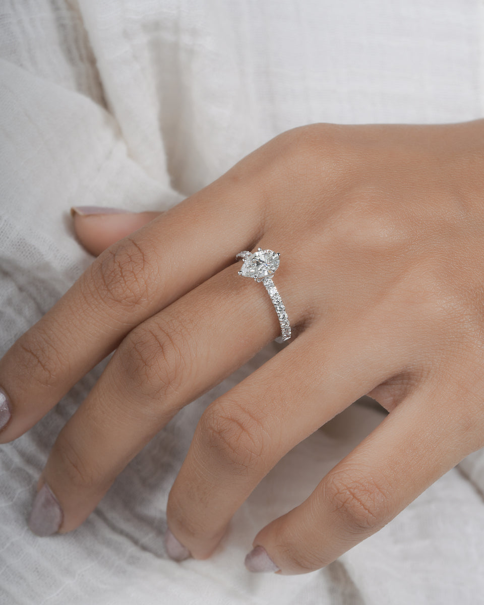  Hand wearing pear cut lab grown diamond engagement ring in white gold.
