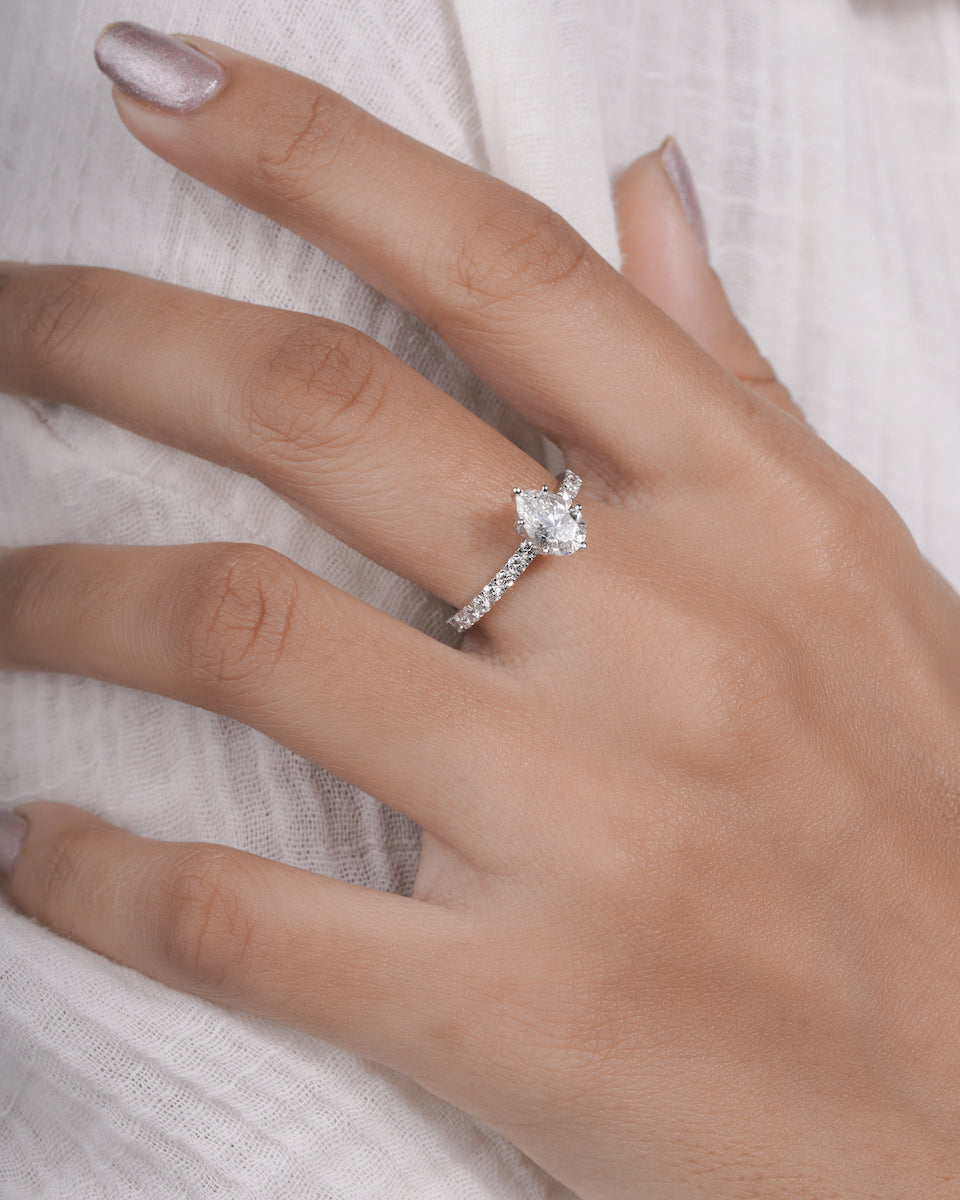  Hand wearing pear cut lab grown diamond engagement ring in white gold.
