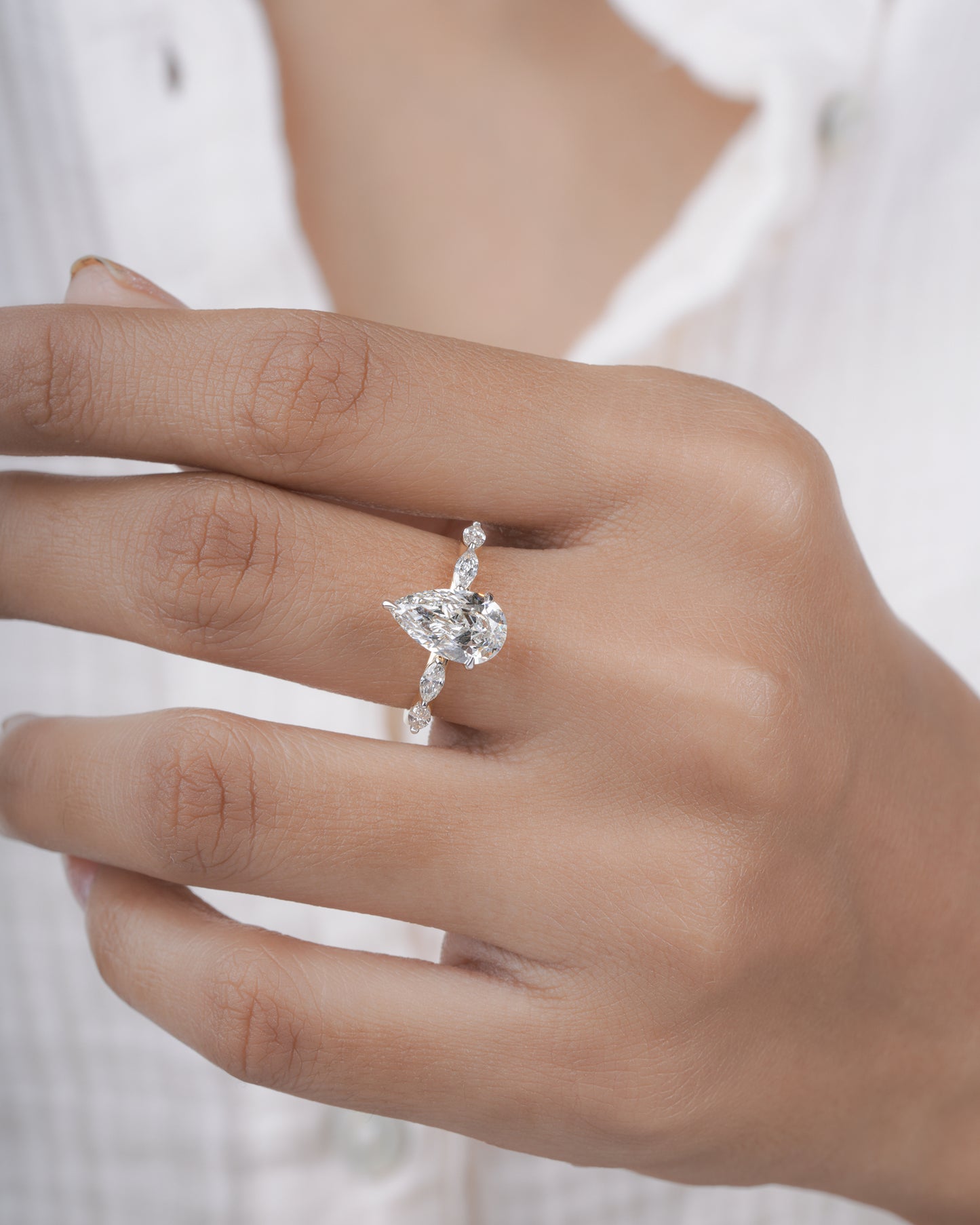 Diamond ring with pear-shaped center stone on a hand.