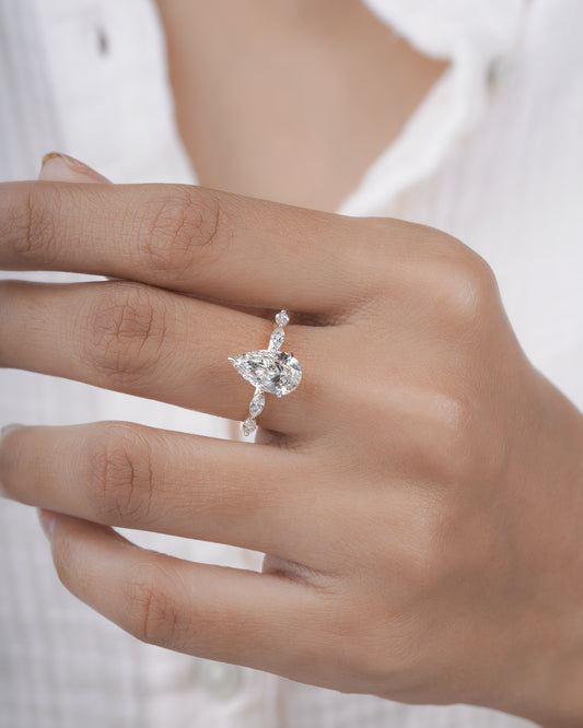 Diamond ring with pear-shaped center stone on a hand.