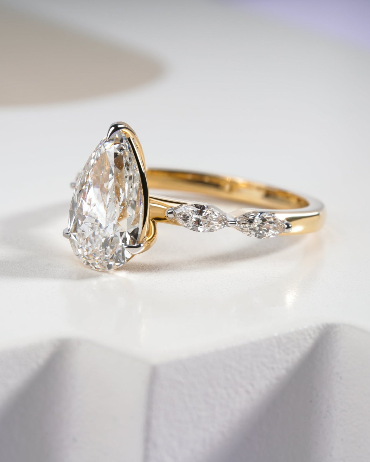 Gold ring with a pear-shaped diamond on a white background