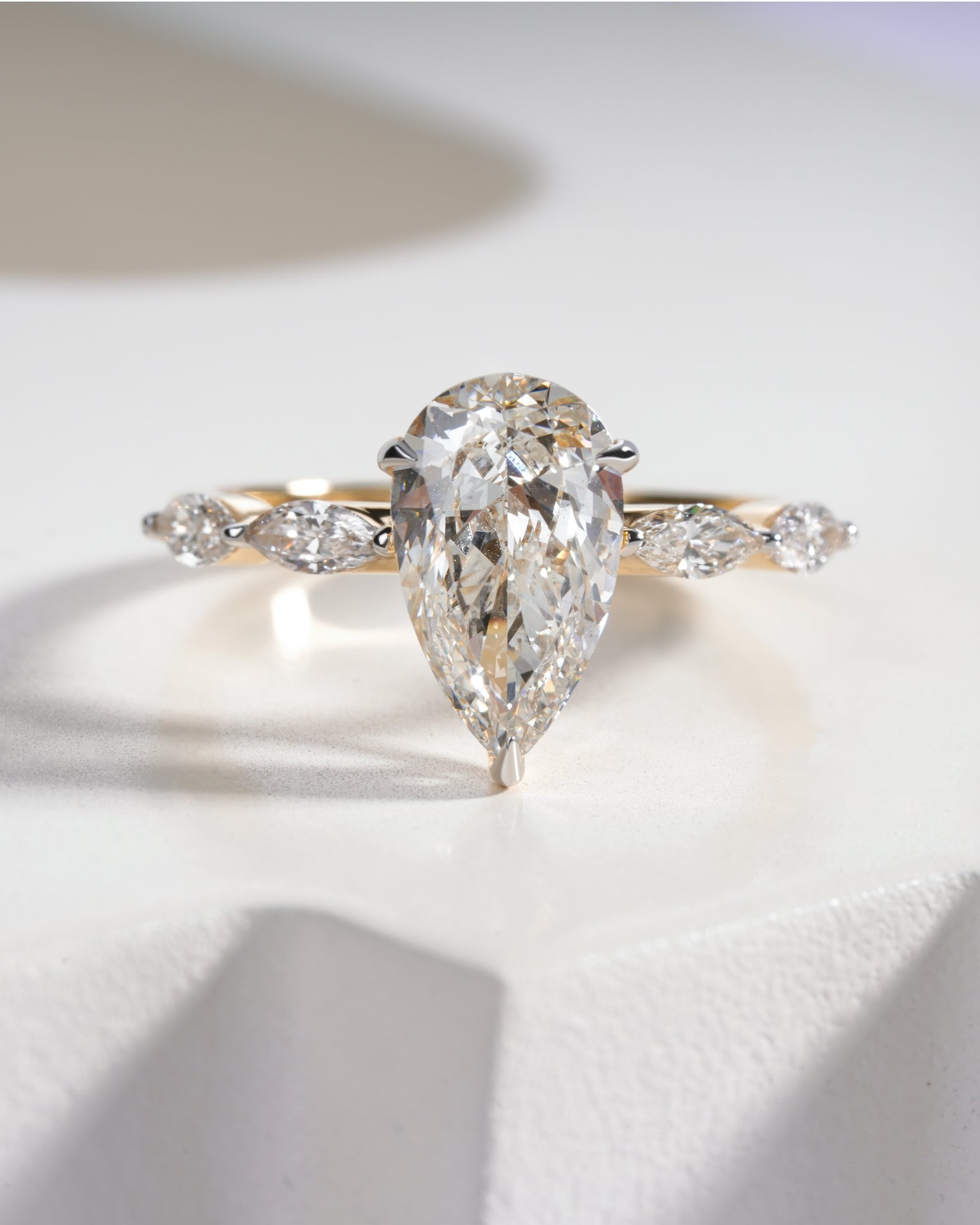 Diamond ring with pear-shaped center stone on a white background