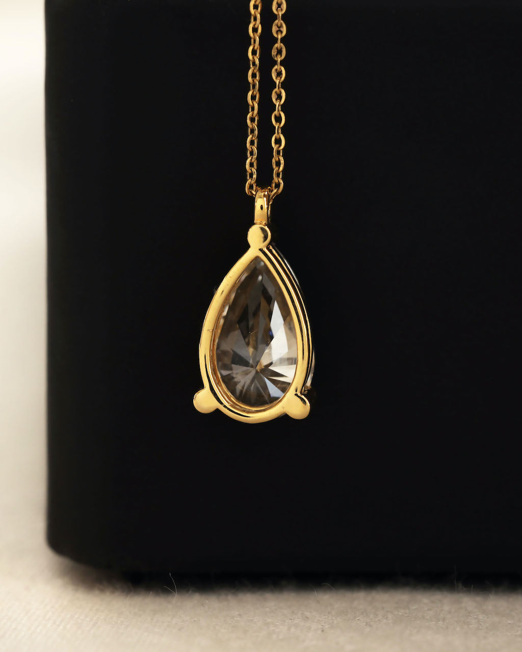 Close up shot of a pear cut lab diamond solitaire pendant necklace in yellow gold.