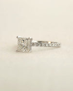 Princess cut diamond engagement ring displayed on a white background.