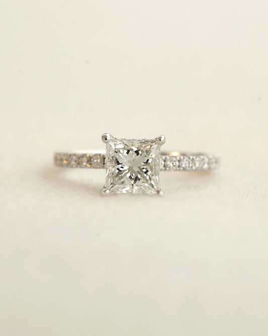 Close up shot of princess cut diamond engagement ring displayed on a white background.