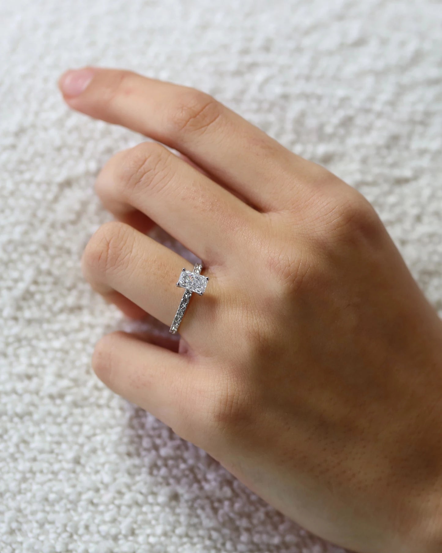 Hand wearing radiant cut diamond ring.