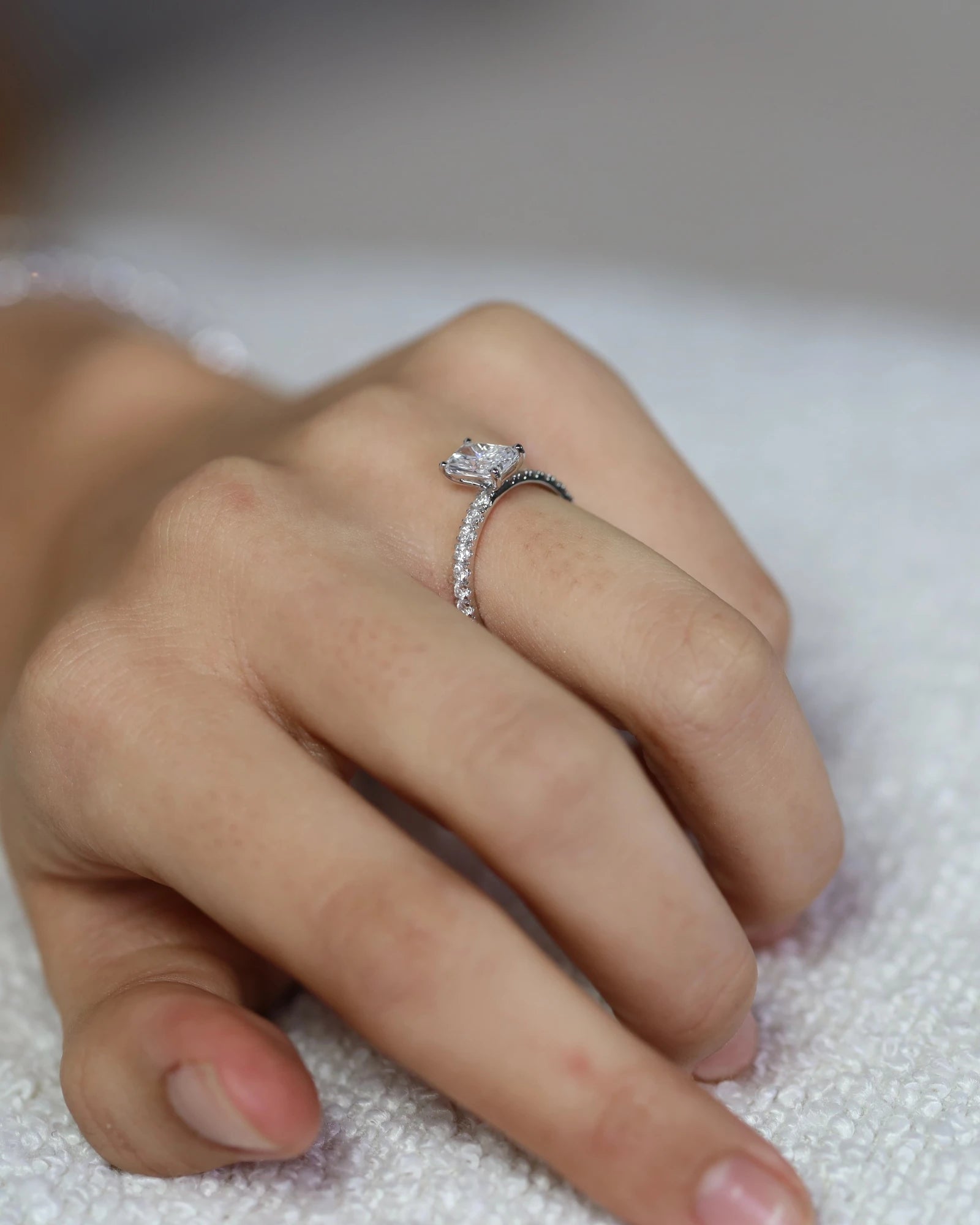 Hand wearing radiant cut diamond ring.