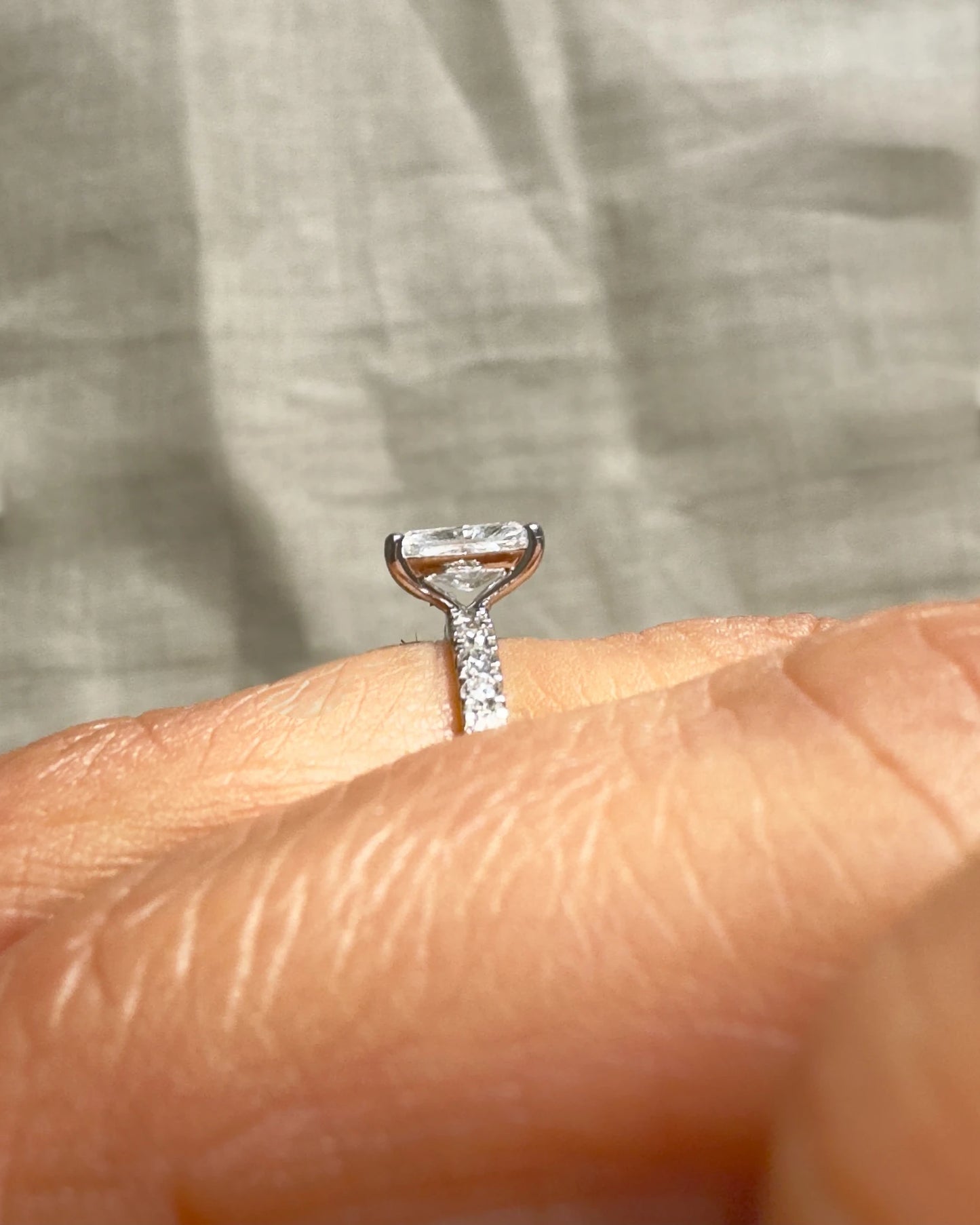 Hand wearing radiant cut diamond ring.