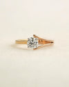 Round cut diamond ring with modern split v band on a light background.