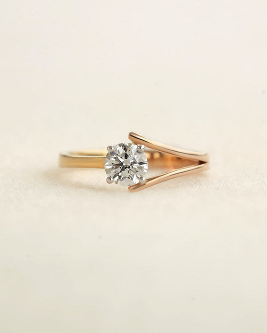 Round cut diamond ring with modern split v band on a light background.