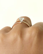 Hand wearing round cut diamond ring with modern split v band in yellow & rose gold.