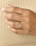 Hand wearing round cut diamond ring with modern split v band in yellow & rose gold.
