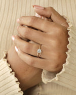 Hand wearing round cut diamond ring with modern split v band in yellow & rose gold .
