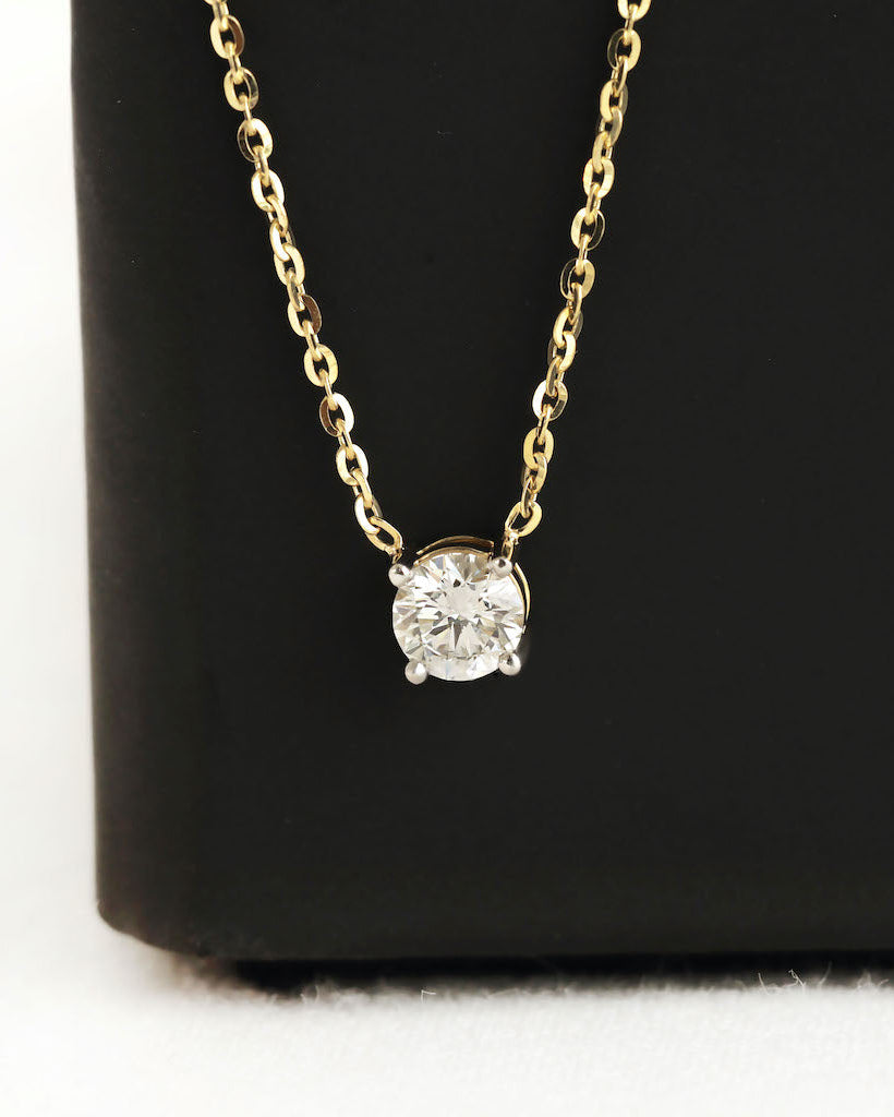 Close up shot of round cut lab diamond solitaire pendant necklace in yellow gold.