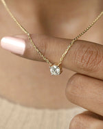 Person wearing round cut lab diamond solitaire pendant necklace in yellow gold.
  
