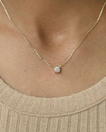 Person wearing round cut lab diamond solitaire pendant necklace in yellow gold.
  