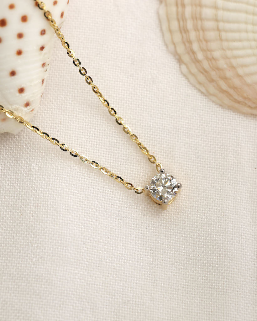 Close up shot of round cut lab diamond solitaire pendant necklace in yellow gold.