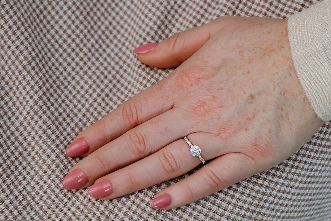 Hand wearing a diamond ring on a checkered fabric background