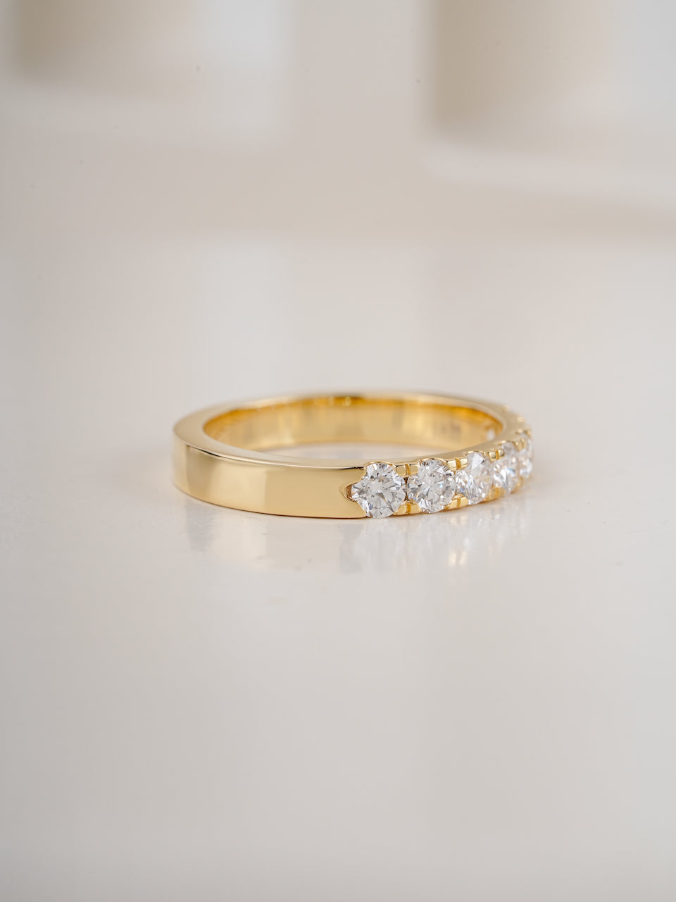 seven stone diamond ring in yellow gold on white background
