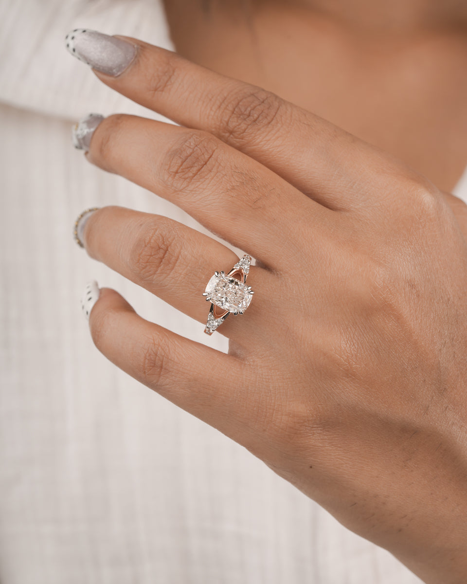 A close-up of a hand wearing a silver-toned ring with a large clear rectangular gemstone and smaller side stones, against a soft white textured background.